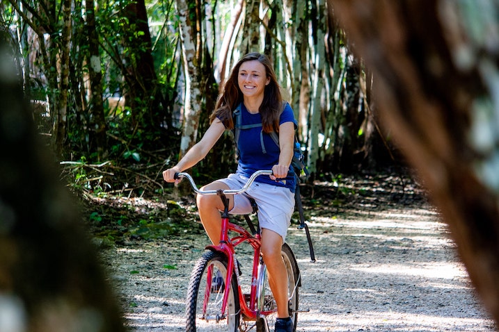 Eine Frau fährt Fahrrad auf dem Gelände der Coba Mayaruine in Yucatan