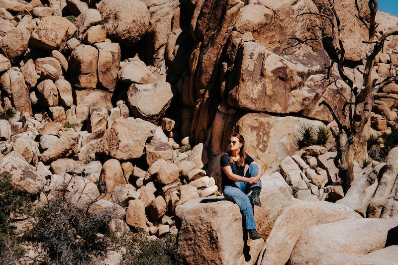 Frau sitzt auf einem Stein im Hidden Valley im Joshua Tree Park