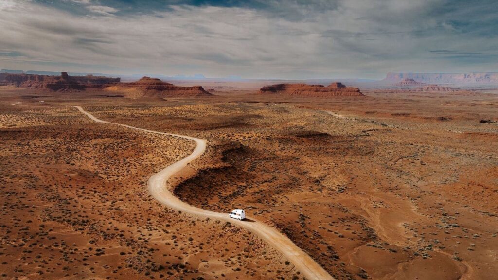 Ein weißer Mercedes Sprinter fährt durch das Valley of the Gods in Utah. Es ist eine Drohnenaufname, die mit einer DJI Mavic Mini aufgenommen worden ist. Mit der Helden Drohnenversicherung ist der Drohnenpilot auch in den USA versichert