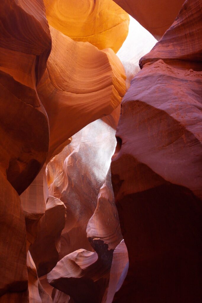 Ein sanfter Lichtstrahl erleuchtet die geschwungenen Sandsteinwände des Lower Antelope Canyons, unterstreicht die warmen Farbtöne und schafft ein magisches Schauspiel, das die Schönheit sowohl des Lower als auch des Upper Antelope Canyons einfängt.
