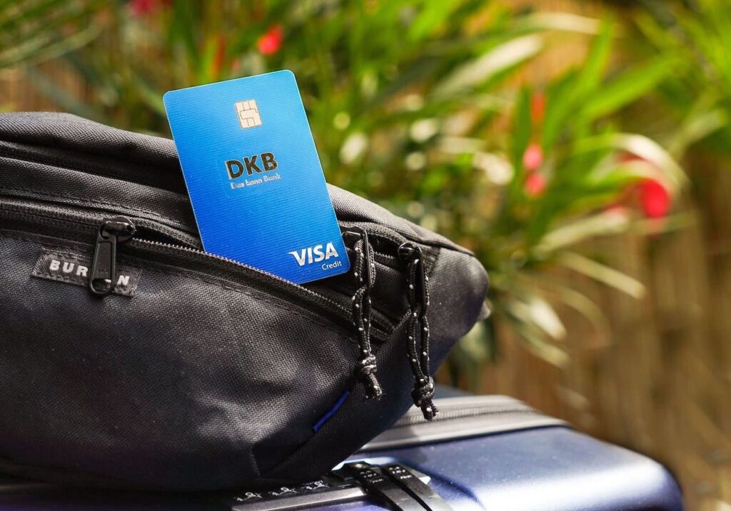 Eine DKB Reisekreditkarte schaut aus einem schwarzen Brustbeutel raus und kann gleich für das kostenlose Geld abheben oder bezahlen im Ausland eingesetzt werden