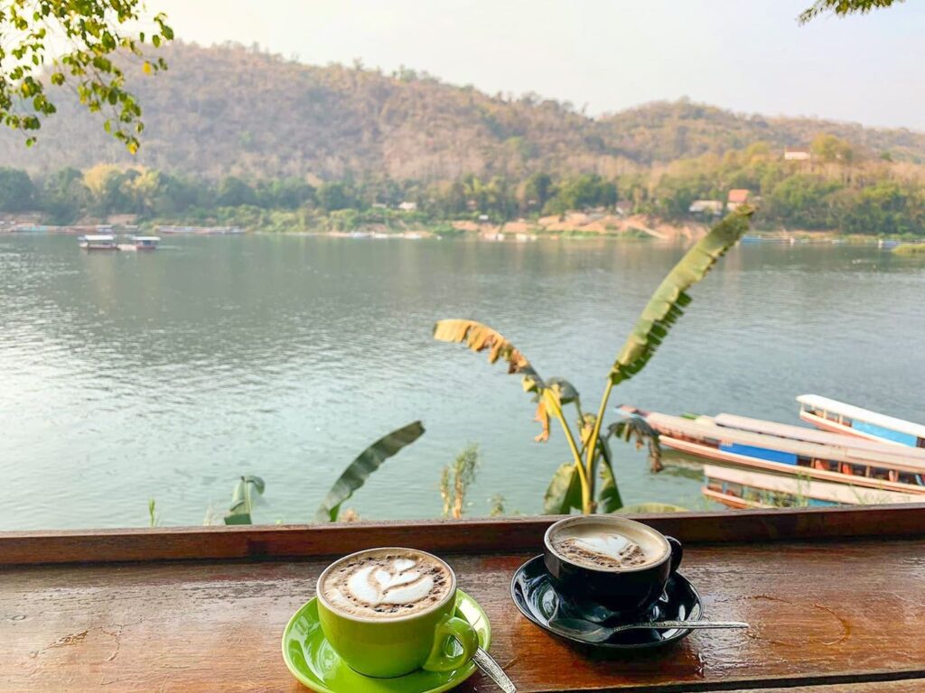 Das Bild zeigt zwei Cappuccinos und im Hintergrund sieht man den Mekong Fluss in Laos.