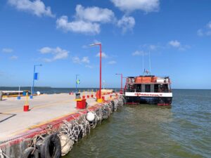 Am linken Rand sieht man den Pier von Chiquila in Yucatan, Mexiko. Im Hafen liegt die rote Fähre von Holbox Ferry, die Touristen nach Holbox bringt.