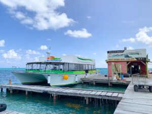 Eine grüne Fähre von Belize Watertaxi Express mit Sitzmöglichkeiten auf und unter Deck, die im Hafen von Caye Caulker liegt und zurück nach Belize City fährt